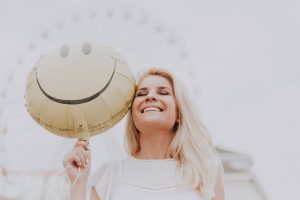 a person smiling while holding a balloon